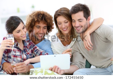 Group of friends looking at pictures on tablet