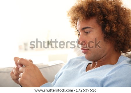 Man in sofa playing with smartphone