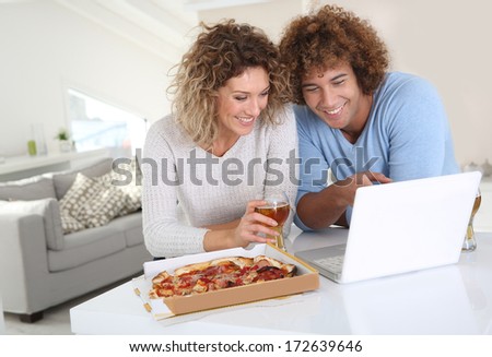 Couple eating pizza and websurfing on internet