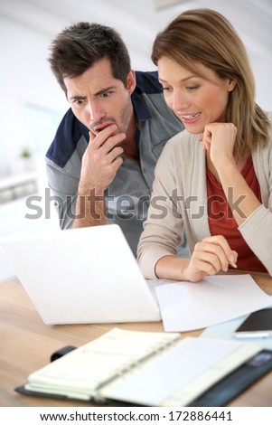 Couple at home checking accounts on internet
