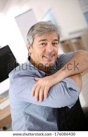 Smiiling mature man relaxing in office chair