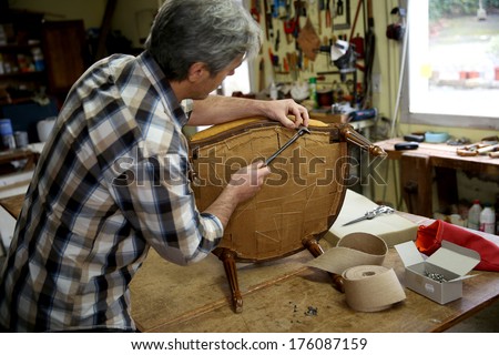 Craftsman repairing antique armchair in workshop