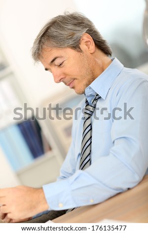 Senior businessman relaxing at work with tablet
