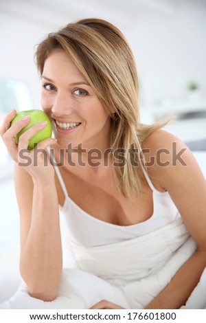 Beautiful woman giving bite to green apple