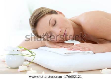 Attractive woman relaxing with eyes shut on massage bed