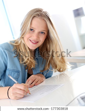 Smiling blond girl filling school application form