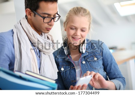 Friends in school listening to music with smartphone