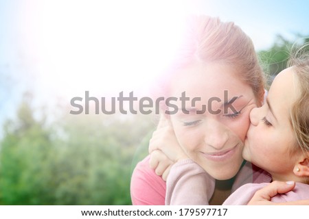 Portrait of little girl giving kiss to her mom