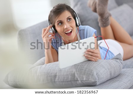 Smiling brunette girl listening to music relaxed on sofa