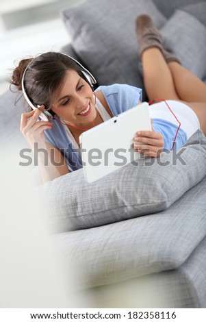 Smiling brunette girl listening to music relaxed on sofa