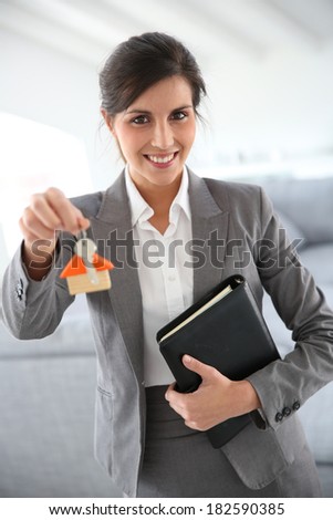 Smiling real-estate agent holding home key t