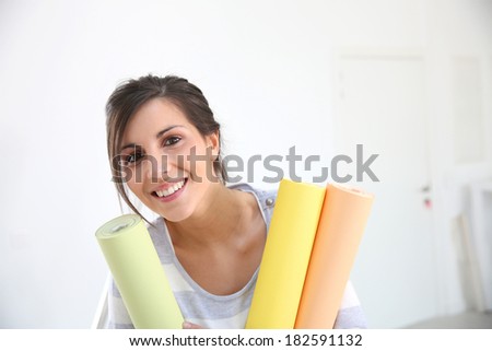 Portrait of cheerful girl holding wallpaper rolls