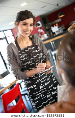 Smiling young waitress taking order in restaurant