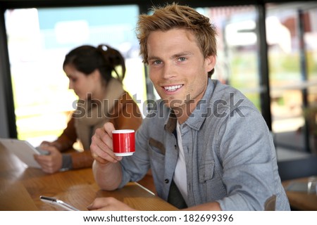 Young man in coffee shop wonnected on smartphone