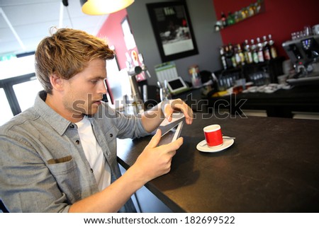 Young man in coffee shop websurfing on internet