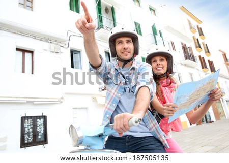 Tourists in Ibiza with scooter looking at city map