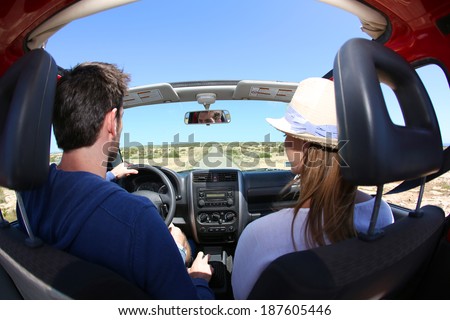 Back view of couple driving convertible car