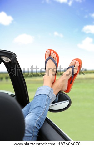 Closeup of feet with flip flops showing by car window