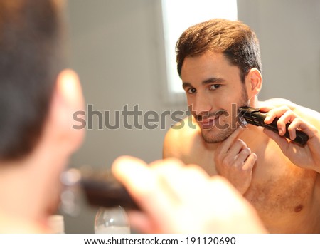 Man using electric shaver in bathroom