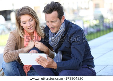 Couple of tourists using digital tablet in town