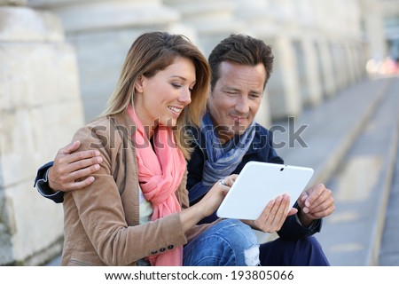 Couple of tourists using digital tablet in town