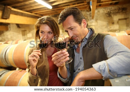 Oenologists in wine cellar tasting red wine