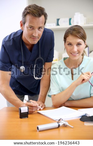 Nurse having doctor signing prescription