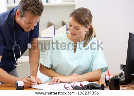 Nurse having doctor signing prescription