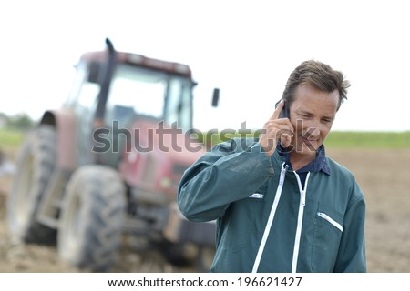 Farmer walking in field and talking on mobile phone