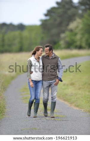 Cheerful 40-year-old couple walking in countryside
