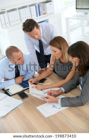 Group of business people meeting around table with tablet