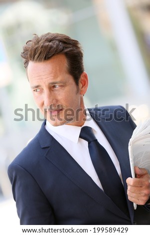 Handsome businessman in town holding newspaper