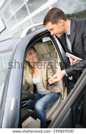 Car dealer giving key to new car owner