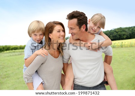 Parents giving piggyback ride to kids in countryside