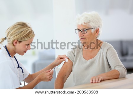 Nurse making vaccine injection to elderly patient