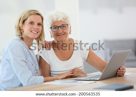 Homecarer with elderly woman using laptop computer