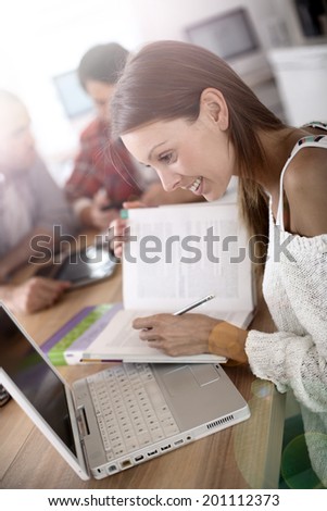 Girl in class studying with laptop and school book