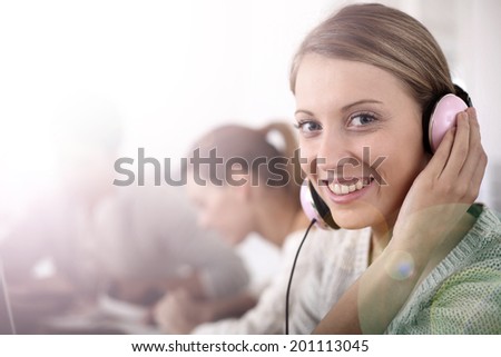 Blond girl in class with music headphones on