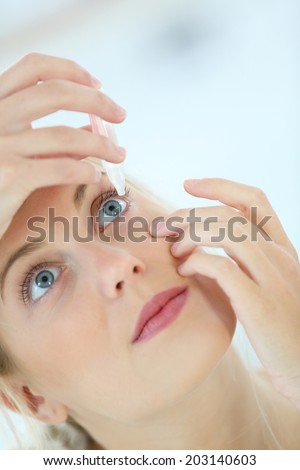 Young woman putting eye drops