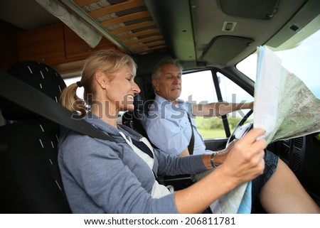 Senior couple riding camper and reading road map
