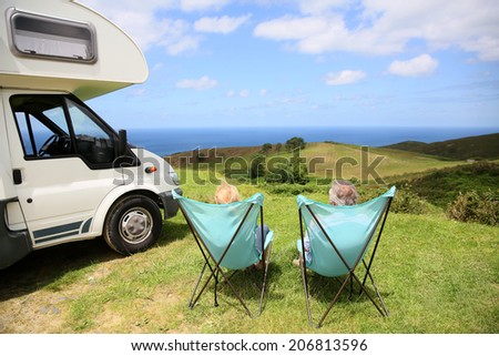 Senior couple relaxing in camping folding chairs, sea landscape