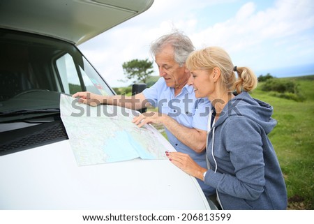 Senior people reading road map by camper