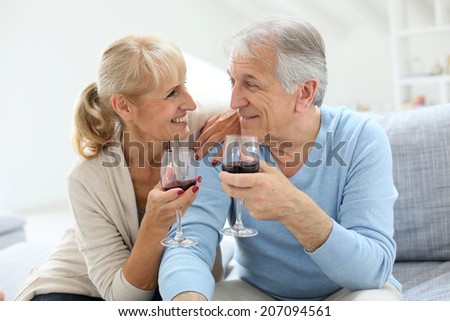Cheerful senior couple cheering with glass of wine