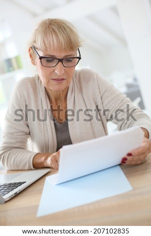 Senior woman filling form online with laptop