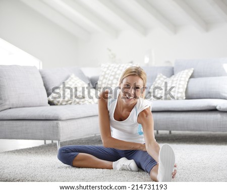 Young woman at home stretching out after exercising