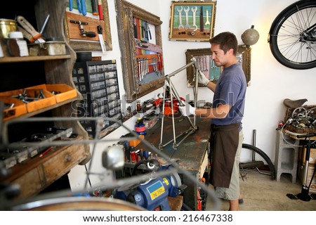 Man in bicycle shop fixing bike frame