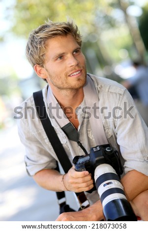 Portrait of handsome photographer holding camera