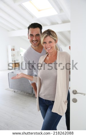 Cheerful mature couple standing at home front door
