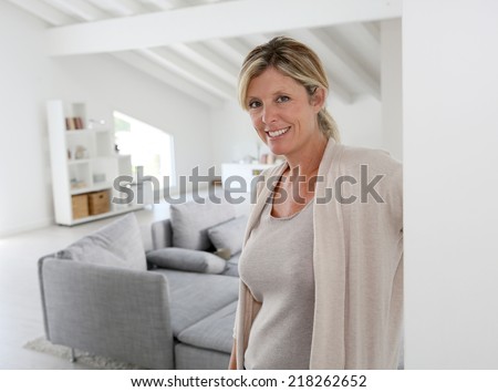 Mature woman welcoming people to come inside her home