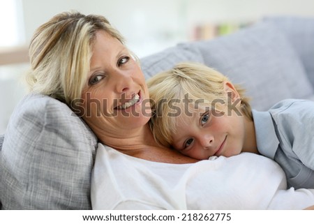 Portrait of happy mom and son relaxing on couch